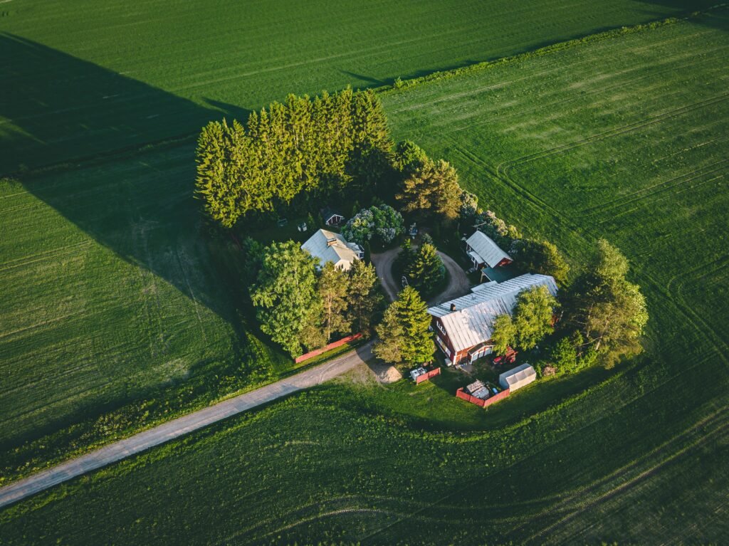Aerial view of farmland with red barn and houses and harvest field in rural Finland