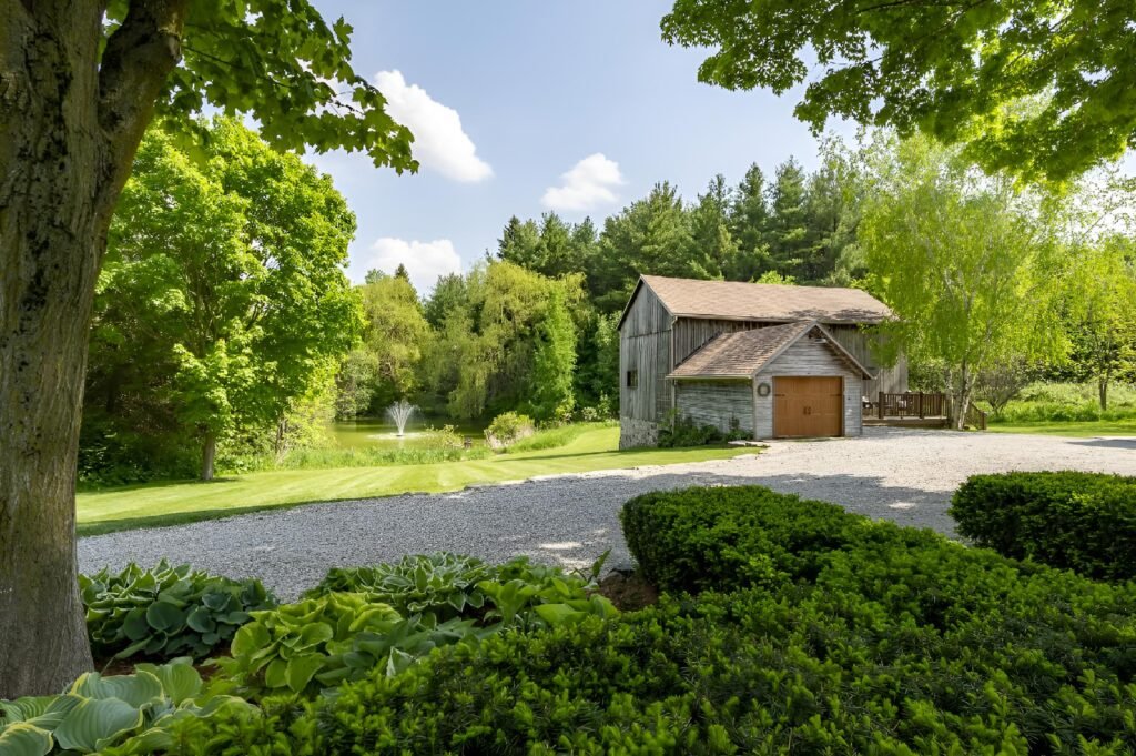 A home nestled among lush trees and shrubs, with a driveway leading up to the house