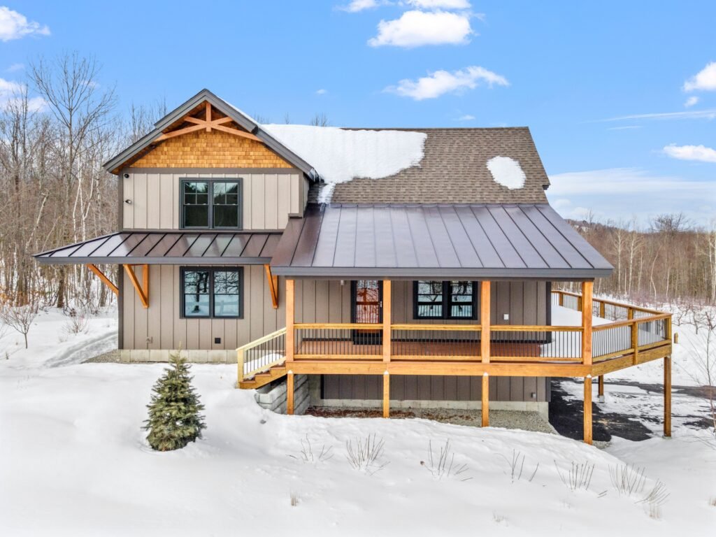 A cozy and inviting custom home situated in a winter landscape, surrounded by snow-covered trees
