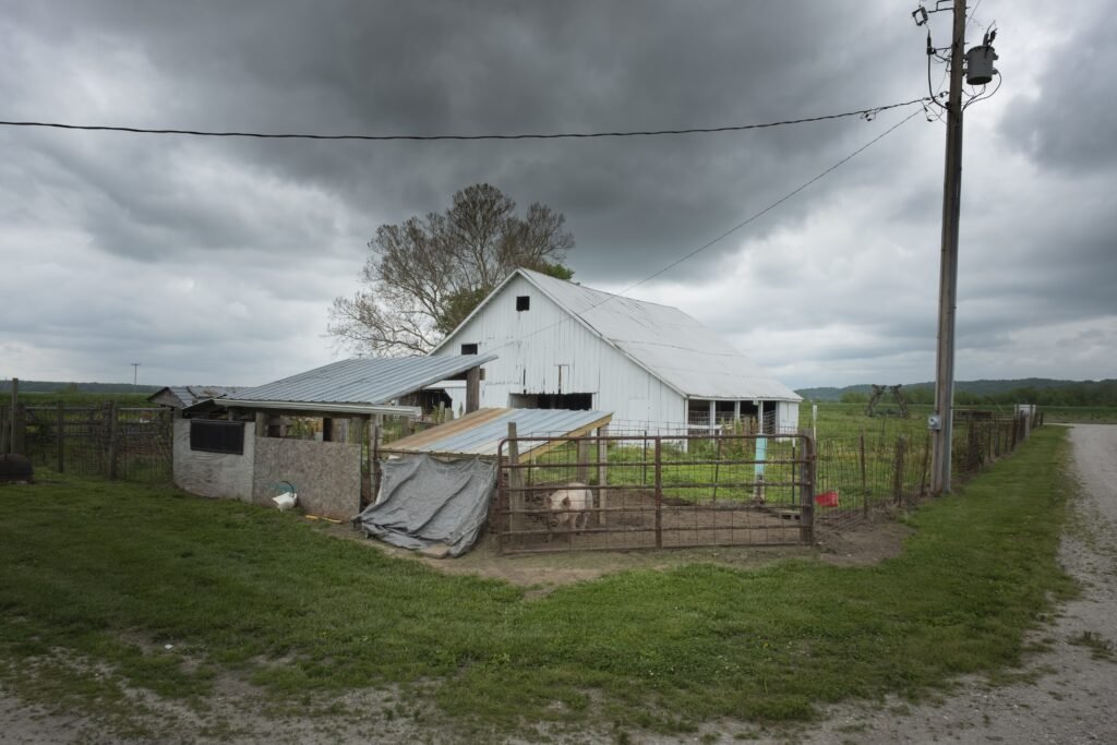 An eye-level gloomy shot of an old white barn on a cloudy day