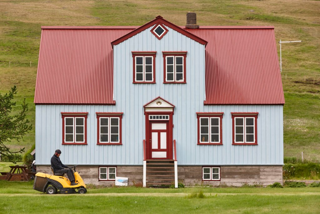 Icelandic gardener working in his cottage with lawn mower. Iceland